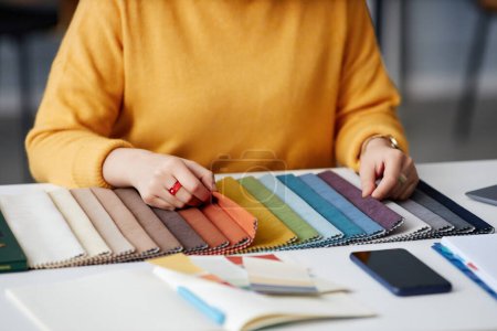 Téléchargez les photos : Gros plan du concepteur choisissant la couleur sur la palette colorée tout en étant assis à son lieu de travail - en image libre de droit