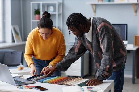 Foto de Un par de diseñadores eligen el color para el interior en la paleta durante su trabajo en equipo en la oficina - Imagen libre de derechos