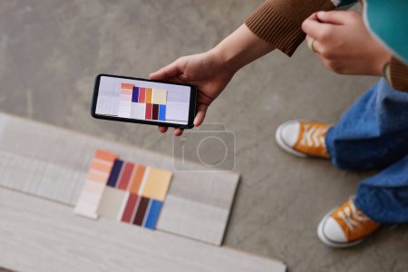 Téléchargez les photos : Vue grand angle de designer faisant photo de différentes couleurs de plancher sur son smartphone - en image libre de droit