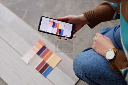 Téléchargez les photos : Vue grand angle du concepteur choisir la couleur pour le plancher et faire des photos sur son smartphone - en image libre de droit