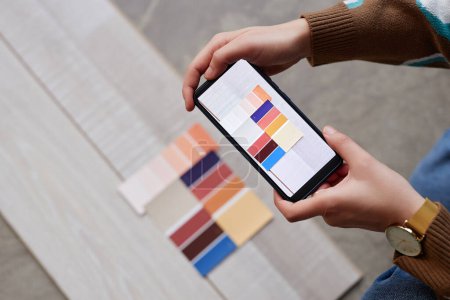 Téléchargez les photos : Vue grand angle du concepteur sélectionnant la couleur pour le plancher et faisant la photo sur son smartphone pour le client - en image libre de droit