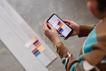 Téléchargez les photos : Designer féminin utilisant un smartphone pour faire une photo de la palette de couleurs pour choisir la couleur pour le plancher - en image libre de droit