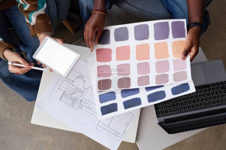 Téléchargez les photos : Vue de dessus des concepteurs examinant le plan directeur et les motifs colorés à la table, ils travaillent sur le projet de nouvelle construction - en image libre de droit