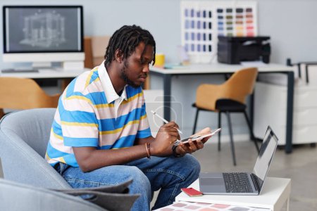 Téléchargez les photos : Projet de dessin de designer afro-américain sur tablette numérique pendant son travail au bureau - en image libre de droit