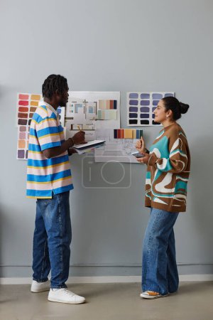 Téléchargez les photos : Image verticale d'un couple de concepteurs planifiant travailler ensemble debout près du mur avec des palettes - en image libre de droit