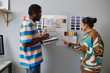 Téléchargez les photos : Designers d'intérieur discuter projet sur le mur ensemble tout en restant au bureau - en image libre de droit