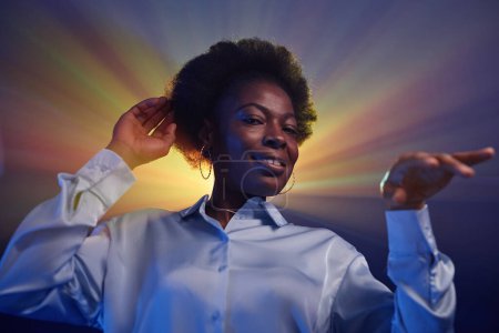 Téléchargez les photos : Portrait de fille noire rétro dansant dans un halo de lumières stroboscopiques et regardant la fête disco de la caméra des années 80 - en image libre de droit
