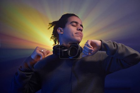 Téléchargez les photos : Portrait de jeune homme noir dansant dans un halo de lumières stroboscopiques à une fête disco rétro - en image libre de droit