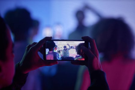 Téléchargez les photos : Gros plan de l'homme filmant DJ lors d'une soirée disco via smartphone, mise au point sur l'écran du smartphone, espace de copie - en image libre de droit