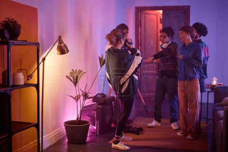 Photo for Full length view at group of young people dancing at house party with girl holding retro video camera and filming home video of friends having fun, copy space - Royalty Free Image