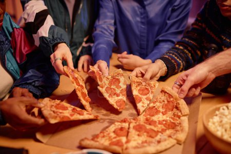 Photo for Closeup of diverse group of friends sharing pizza with pepperoni at house party 80s style, copy space - Royalty Free Image
