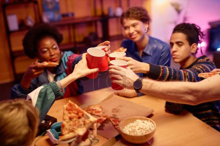 Téléchargez les photos : Gros plan des jeunes grillant avec des tasses rouges sur la table à la fête maison rétro, espace de copie - en image libre de droit