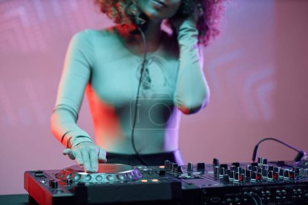 Téléchargez les photos : Gros plan de la jeune femme comme DJ féminine faisant des morceaux de musique à la soirée dans la lumière du néon - en image libre de droit