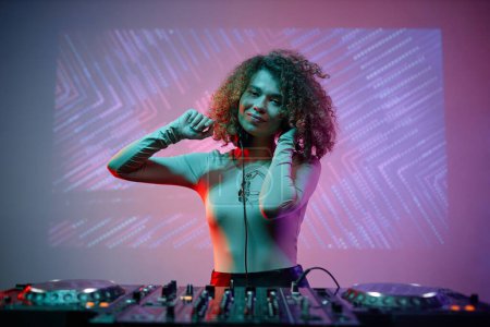 Foto de Retrato de mujer joven como DJ femenina mirando a la cámara en el club nocturno, espacio de copia - Imagen libre de derechos