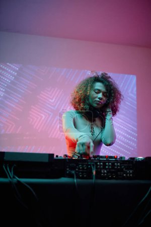 Téléchargez les photos : Portrait de jeune femme en tant que DJ féminine faisant des pistes musicales lors d'une soirée disco au néon - en image libre de droit