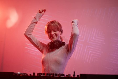 Foto de Retrato de mujer joven como DJ femenina haciendo pistas de música en la fiesta disco en luz de neón - Imagen libre de derechos