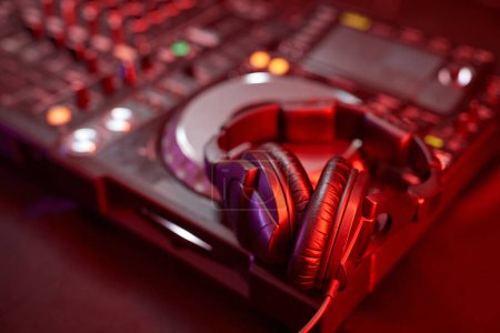 Foto de Primer plano del equipo de DJ, mezclador o tocadiscos en luz de neón con auriculares de estudio, espacio para copiar - Imagen libre de derechos