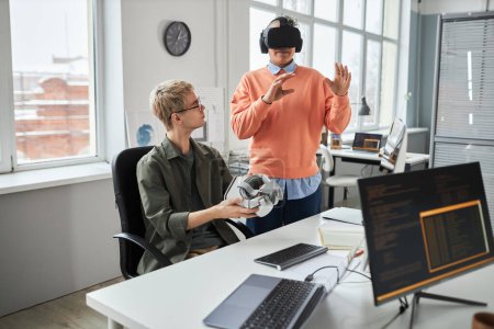 Photo for Young programmer testing new software in VR glasses together with his colleague during teamwork in IT office - Royalty Free Image