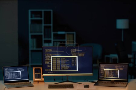 Photo for Dark IT office with computers with codes on monitors standing on table of developer - Royalty Free Image