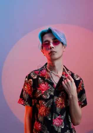 Photo for Portrait of stylish young guy in colored shirt and blue hair looking at camera standing in studio - Royalty Free Image