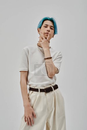 Téléchargez les photos : Image verticale d'un adolescent élégant avec des cheveux bleus posant à la caméra debout sur fond blanc - en image libre de droit