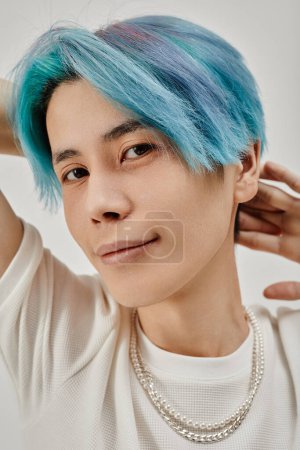 Téléchargez les photos : Image verticale de jeune homme asiatique aux cheveux bleus regardant la caméra - en image libre de droit