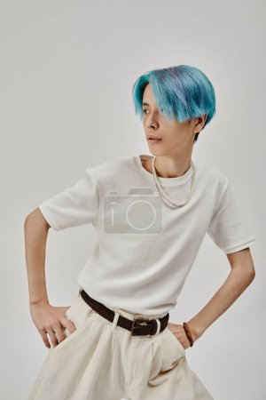 Téléchargez les photos : Image verticale d'un adolescent aux cheveux bleus et vêtu de vêtements blancs montrant des exercices de danse sur fond blanc - en image libre de droit