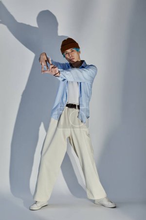Vertical image of young guy in stylish clothing posing and gesturing at camera against white background