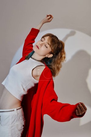 Vertical image of female dancer in red coat exercising on white background