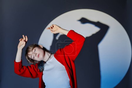 Young professional dancer in red cardigan enjoying her dancing on dark background