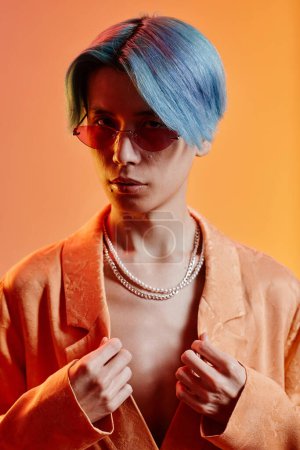 Téléchargez les photos : Image verticale d'un jeune asiatique avec une coiffure bleue et des lunettes de soleil regardant la caméra - en image libre de droit