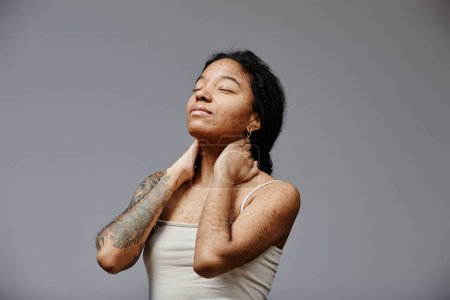 Foto de Retrato mínimo de mujer joven negra con textura de piel real posando con confianza con los ojos cerrados, espacio para copiar - Imagen libre de derechos