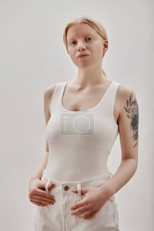 Minimal portrait of blonde girl with tattooes posing against white background