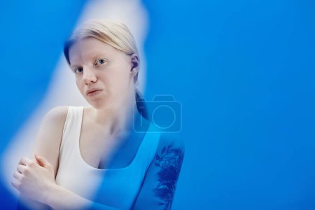 Minimal portrait of ethereal girl with albinism posing in color blue, copy space