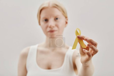 Closeup of young woman with albinism holding yellow ribbon for International awareness day, copy space