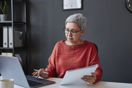 Téléchargez les photos : Portrait d'une femme âgée qui réussit en tant que femme patronne utilisant un ordinateur au bureau - en image libre de droit