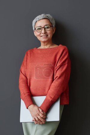 Téléchargez les photos : Portrait de la femme d'affaires senior réussie souriant à la caméra contre le mur - en image libre de droit