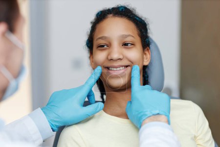 Photo for Portrait of teen black girl with toothy smile sitting in a dental chair at dentistry clinic - Royalty Free Image