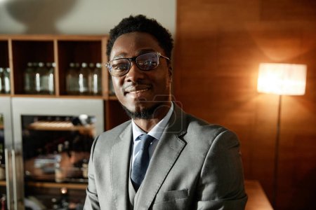 Téléchargez les photos : Portrait de jeune homme d'affaires afro-américain en lunettes souriant à la caméra debout dans le restaurant - en image libre de droit