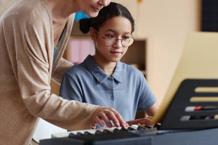 Foto de Joven estudiante aprendiendo a tocar el piano junto con el profesor que le enseña en la clase de música - Imagen libre de derechos