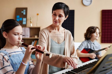 Téléchargez les photos : Professeur mature jouant des instruments de musique avec l'élève pendant la leçon de musique - en image libre de droit