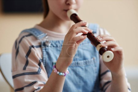 Téléchargez les photos : Gros plan d'une écolière apprenant à jouer de la flûte pendant ses cours à l'école de musique - en image libre de droit