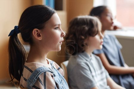 Téléchargez les photos : Vue latérale de l'écolière chantant avec d'autres enfants dans la chorale en classe de musique - en image libre de droit