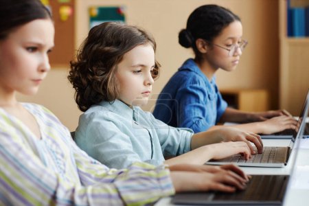 Foto de Grupo de escolares que se concentran en el trabajo en la presentación en línea en computadoras durante la lección en la escuela - Imagen libre de derechos