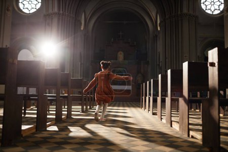 Foto de Vista trasera de la niña corriendo entre los bancos en la iglesia bautista con arquitectura antigua - Imagen libre de derechos