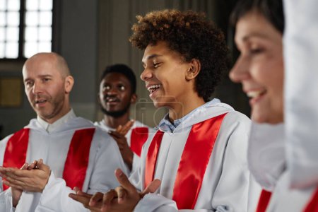 Group of happy people from church choir singing and clapping hands during performance
