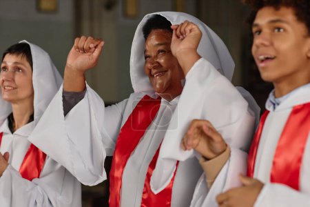Foto de Grupo de personas felices en trajes blancos cantando juntos en el coro de la iglesia - Imagen libre de derechos