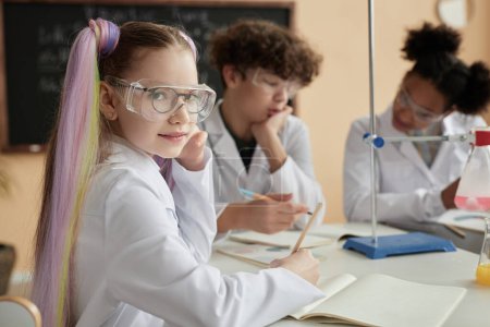 Photo for Portrait of cute schoolgirl with pigtails enjoying science class and looking at camera, copy space - Royalty Free Image