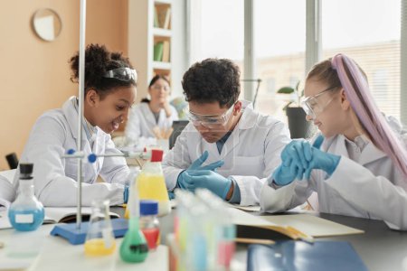 Foto de Grupo de escolares jóvenes que disfrutan de experimentos científicos en clase y trabajan juntos en un examen práctico de química - Imagen libre de derechos