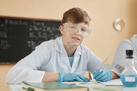 Téléchargez les photos : Portrait d'un adolescent portant un appareil dentaire en classe de sciences à l'école et regardant une caméra - en image libre de droit